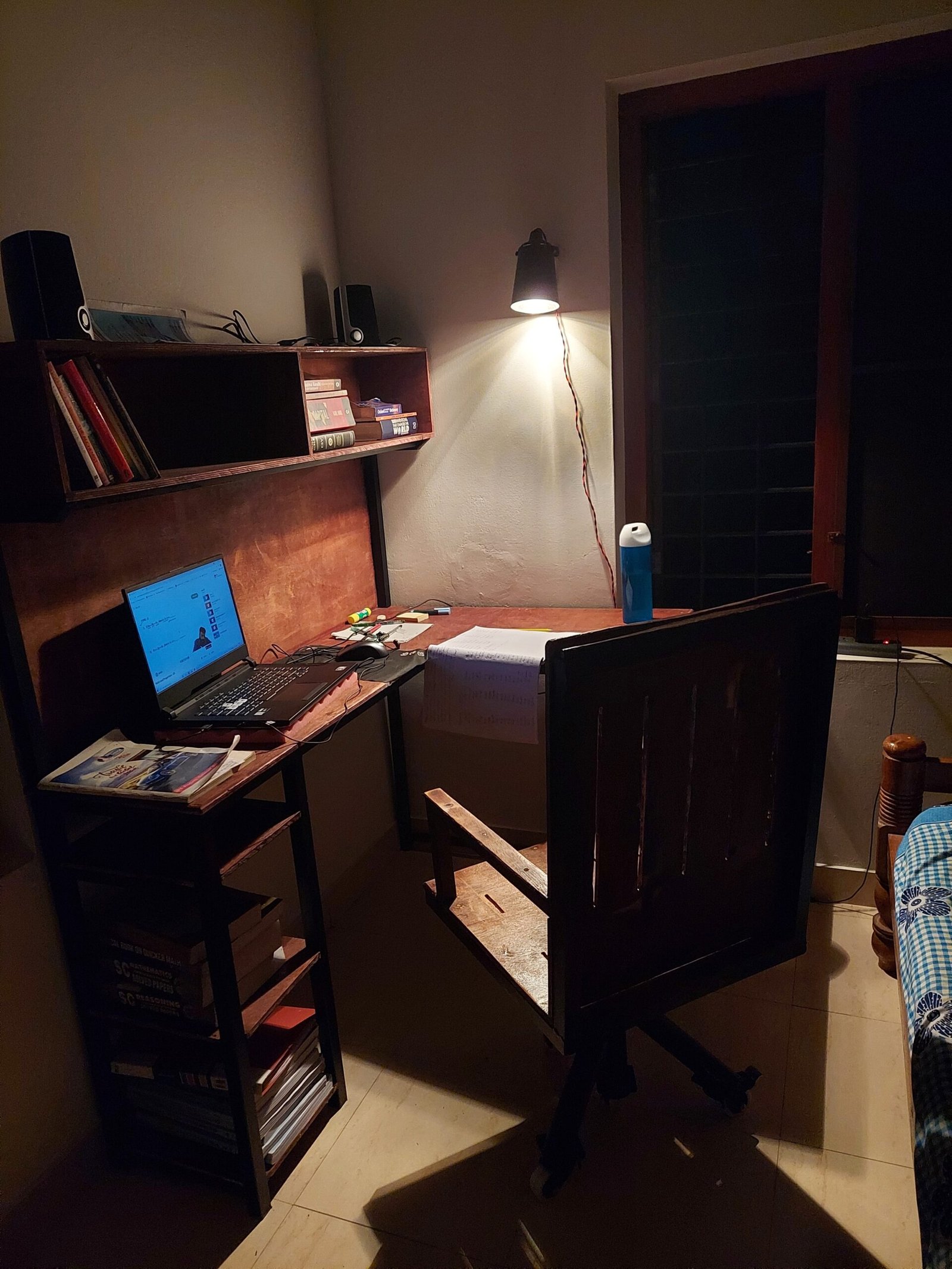 The finished desk in use at night, lit by a handmade desk lamp made from a repurposed jug