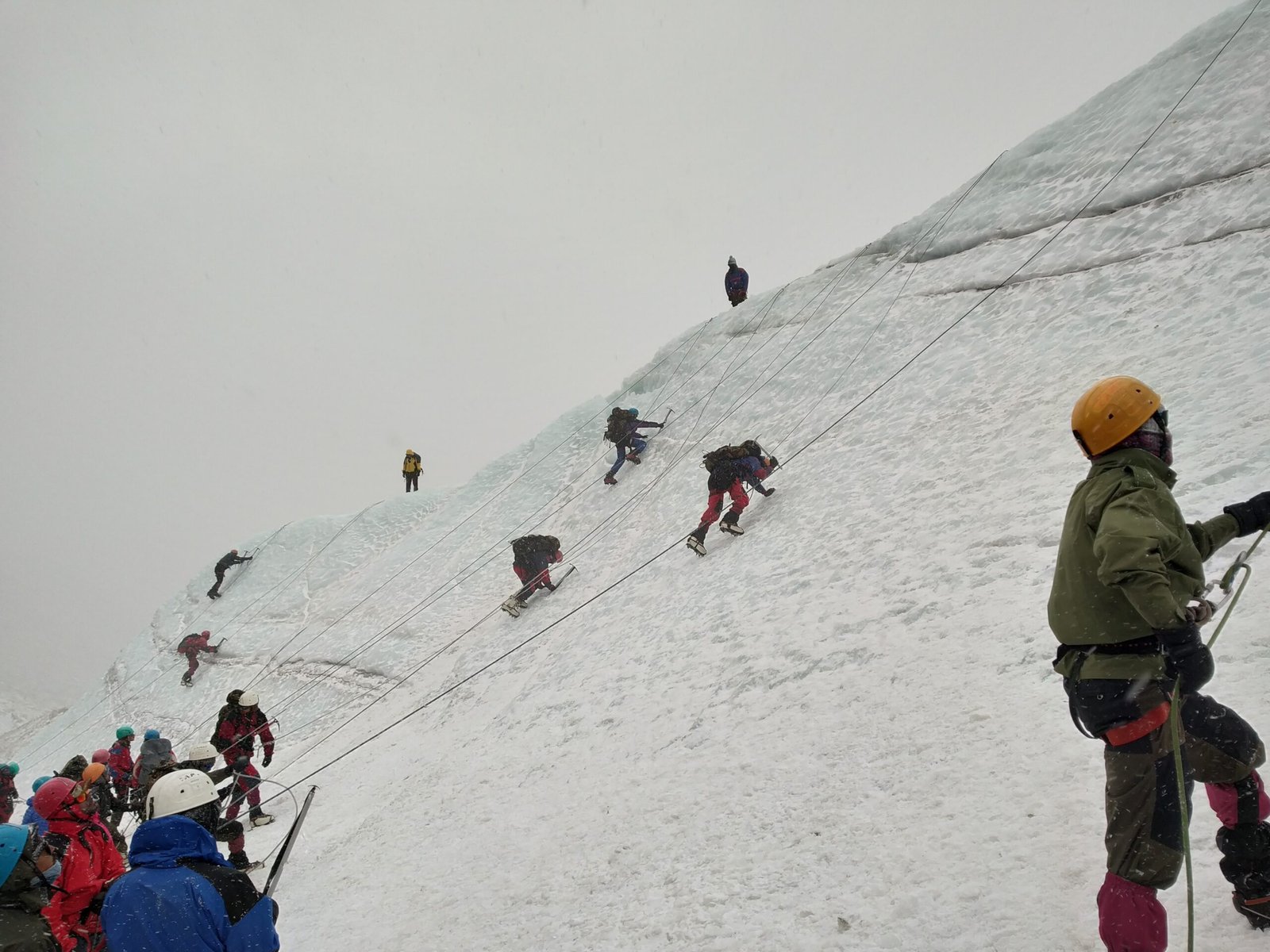Mountaineer seated on rocks with a snow-covered peak in the distance near base camp