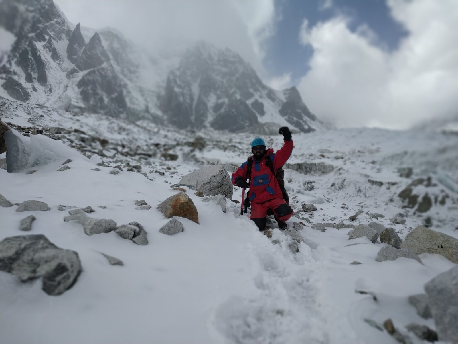 Prayer flags strung across a rocky summit ridge with snow-capped Himalayan peaks behind